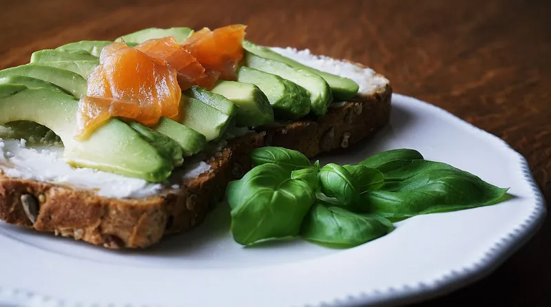 Aguacate fresco cortado sobre una tabla de madera, fuente de grasas saludables